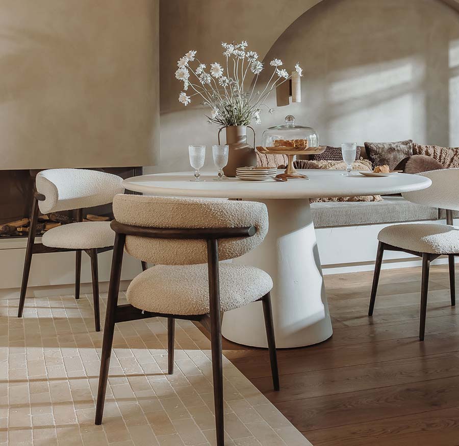 Lichte eethoek met een ronde tafel op een middenpoot en gestoffeerde stoelen met houten poten